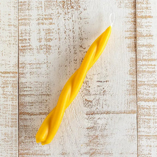 Foto cenital de vela artesana hecha a mano en espiral sobre una mesa rústica blanca. Real Fábrica