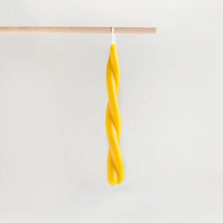 Foto de vela de cera de abeja hecha a mano en España en espiral colgada en una varilla de madera. Real Fábrica