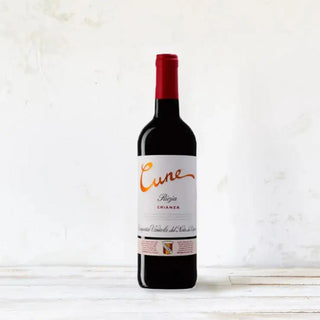 Foto frontal de una botella de rioja cune crianza sobre una mesa de madera. Vino tinto. Real Fábrica.