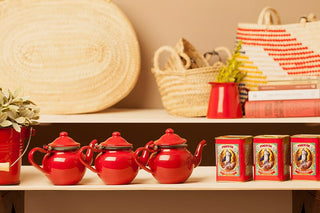 Teteras de peltre esmaltado rojo en cocina con objetos tradicionales